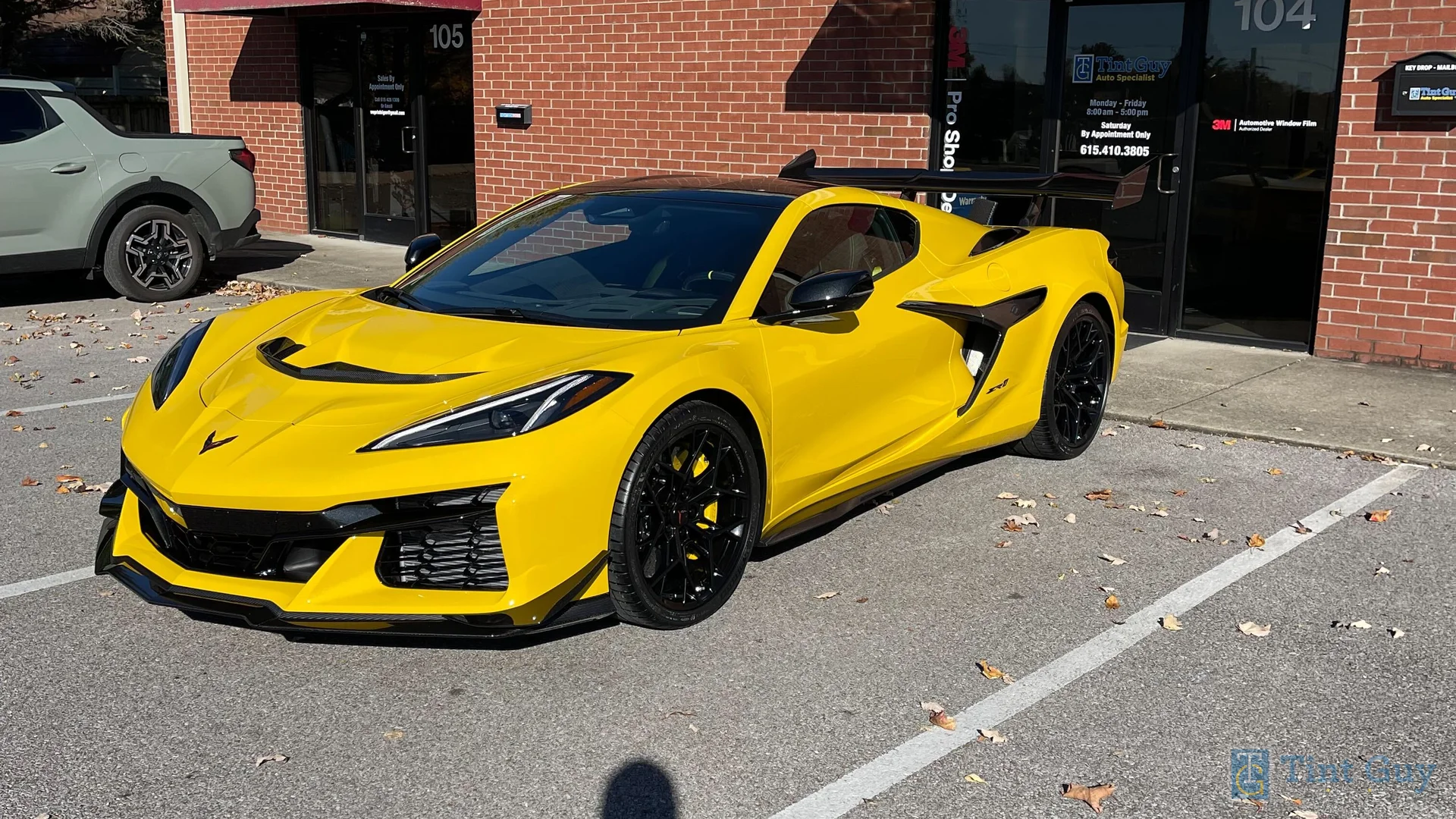Bright yellow Chevrolet Corvette C8 parked in front of Tint Guy LLC shop